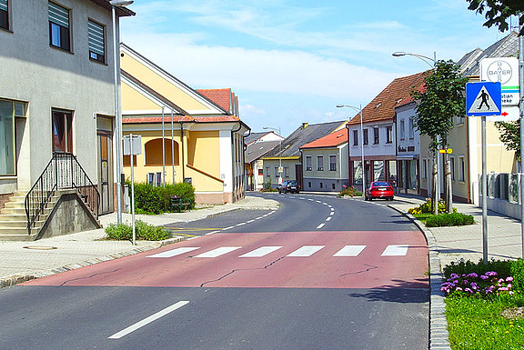 Die Bodenmarkierung für einen Fußgängerübergang auf rotem Untergrund